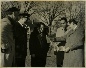 Randolph W. Bromery, Allen Torrey, Fire Chief Doherty, Mike Sullivan, and Jack Littlefield, standing outdoors reading a paper