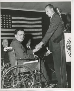 Unidentified man shaking hands with client in wheelchair at Institute Day