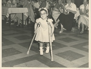 Young girl on crutches in front of a crowd