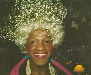 A Photograph of Marsha P. Johnson Smiling and Wearing a Baby's Breath Flower Headpiece