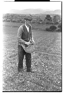 Old farmer sowing seeds from traditional apron, Hilltown, Co. Down