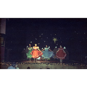 Young girls perform a folk dance on stage during a Three Kings Day celebration.