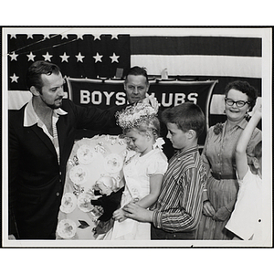 Zachary Scott places a flower crown on Maryann Connolly, the winner of the Boys' Club Little Sister Contest, as her brother John holds her hand