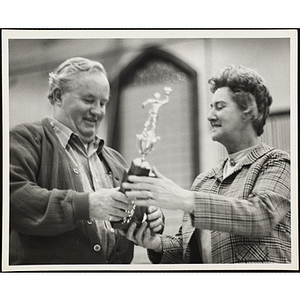 A man receives a trophy in the Boys' Club basketball tournament