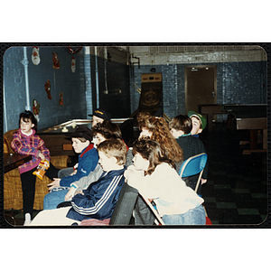 Six boys and three girls sit together, facing left, at the Charlestown Boys & Girls Clubhouse