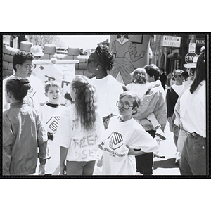 Several Club members wearing Boys and Girls Clubs of Boston t-shirts stand together near an inflatable "Kiddie Kastle" at the Boys and Girls Clubs of Boston 100th Anniversary Celebration Street Fair