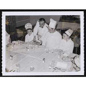 A waiter serves a dish to members of the Tom Pappas Chefs' Club and a chef in a dining room
