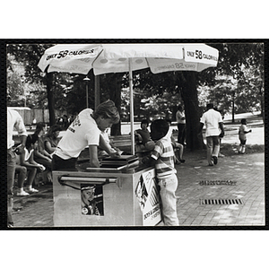 A teenage boy serves ice juice from a food cart to a boy on Boston Common