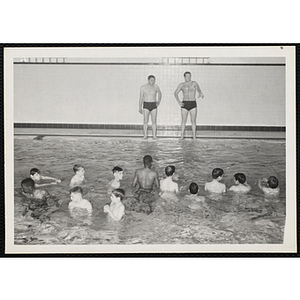 Two men conduct a swim class in a natatorium pool