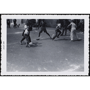 A group of boys with balloons tied to their ankles play a game outdoors on Tom Sawyer Day