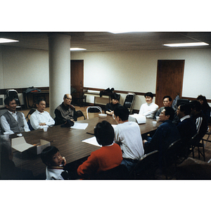 Chinese Progressive Association members sit and hold a meeting at a table