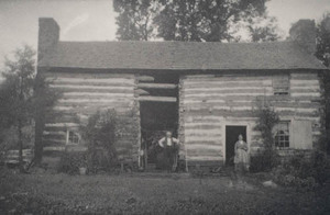Log farmhouse with man and woman standing in front