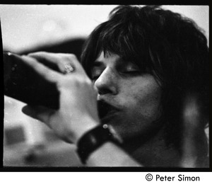Jeff Beck swigging from a bottle behind stage
