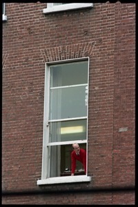 Man leaning out his window overlooking a Dublin street