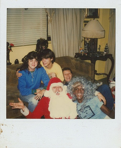 A Photograph of Marsha P. Johnson Wearing Tinsel on Her Head, Posing with "Santa," and Others