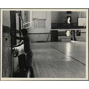 Two men working on a window in the Charlestown Boys' Club gymnasium during the renovation