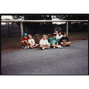 Nine Boys & Girls Club members sit together, posing with a deer behind the fence