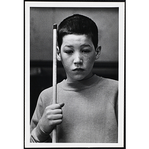 A boy from the Boys' Clubs of Boston holding a cue