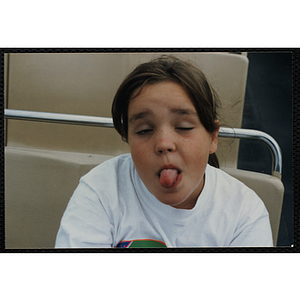 A girl sticks out her tongue on a boat