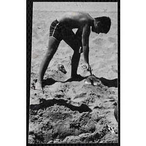 A boy plays in the sand on a beach