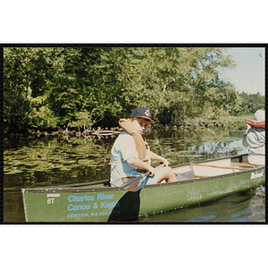 A boy paddles a canoe on a lake with another child