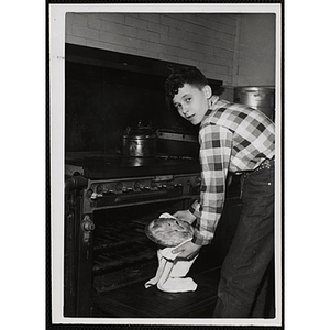 A boy removes a pie from an oven