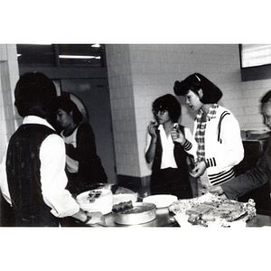 People standing around the potluck buffet table at the 29th anniversary celebration of the People's Republic of China, held at the Josiah Quincy School