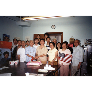 Chinese Progressive Association members gather around a man and women who are cutting cake