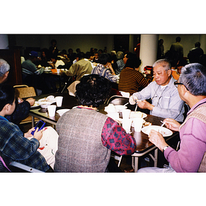 Association members sit at tables, eating Thanksgiving dinner