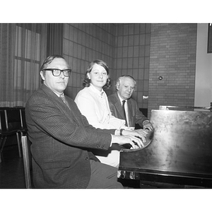 Professor Ray Robinson sits at a piano with two others