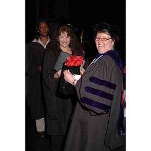 Faculty member presents student with certificate and gift bag at School of Nursing convocation