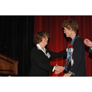 Emily A. Spieler, Dean, School of Law greets Outstanding Alumni Award recipient Margot Botsford at the podium at the Alumni Ball