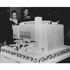 Two students cut into the Ell Student Center addition replica cake at the dedication ceremony