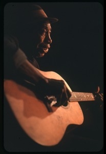 Mississippi John Hurt: studio portrait, seated, playing guitar