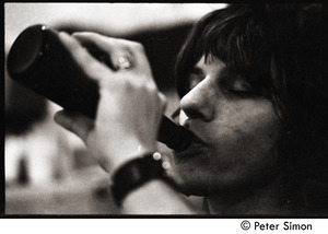 Jeff Beck swigging from a bottle behind stage