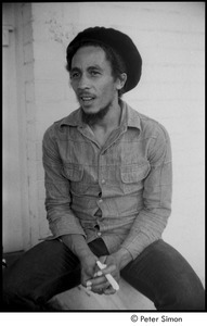 Bob Marley holding a joint the steps of his home