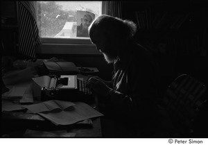 Ram Dass at typewriter: Ram Dass typing, with a portrait of Neem Karoli Baba in the background