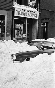 Car buried in snow in front of Fun Travel Service on Parameter Street