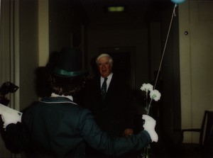 Woman dressed in green with flowers and balloon greeting Thomas P. O'Neill