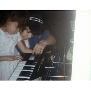 Two little girls playing a keyboard.