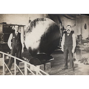 Two men standing next to a propeller blade