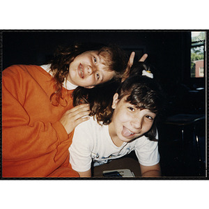 A girl making a V-sign while leaning over another girl at the Boys and Girls Club