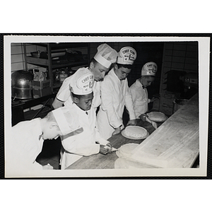 Four members of the Tom Pappas Chefs' Club decorate cakes under the tutelage of a baker in a kitchen