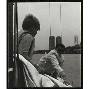 A boy and a man occupy a sailboat in Boston Harbor