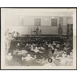 A large group of boys swim in a natatorium pool