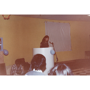 Woman at a Chinese Progressive Association event speaks at a podium