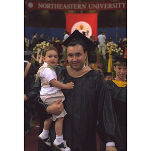 Graduate holding his son at commencement