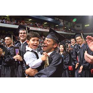 Graduate holding child at commencement ceremony