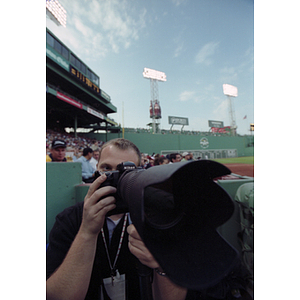 Adam Hunger taking a photograph at a Boston Red Sox game
