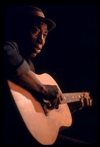 Mississippi John Hurt: studio portrait, seated, playing guitar